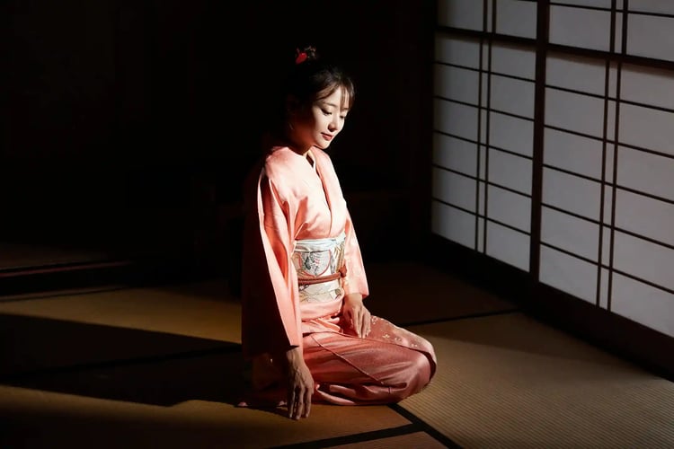 A woman sitting in a Japanese-style room, embodying the spirit of omotenashi (Japanese hospitality)
