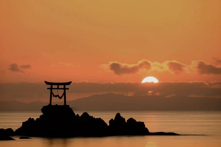 A torii gate in the sea at sunset