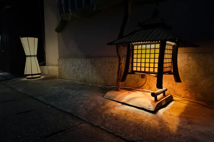 A back alley illuminated by andon and stone lanterns