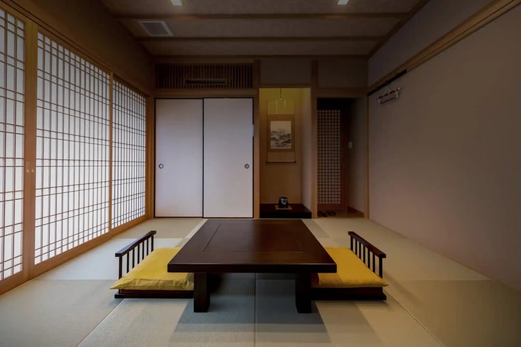 A Japanese-style room with a low table and zaisu chairs, where soft sunlight streams in through the shoji screens