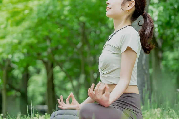A woman practicing yoga with a smile, surrounded by greenery