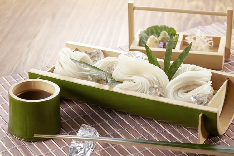 Somen noodles served in a bamboo bowl, giving off a cool and refreshing vibe