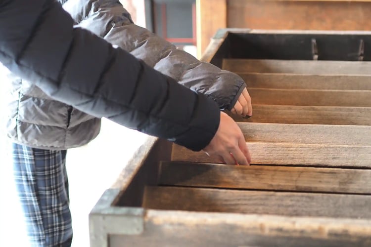 Hands of a parent and child making an offering (to the shrinetemple)