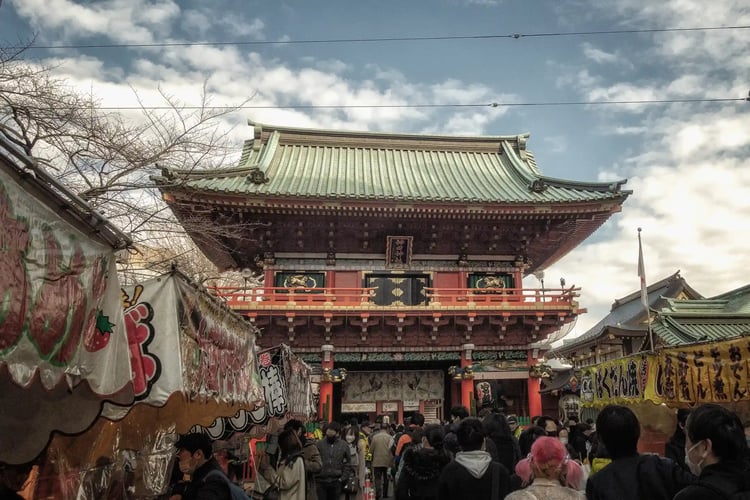 A scene of Hatsumode (New Year_s first visit) at Kanda Myojin Shrine, featuring the Zuishinmon gate and stalls