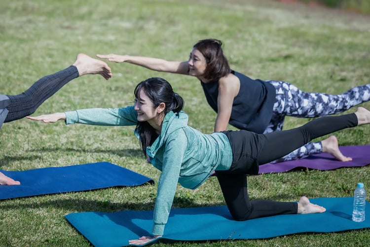 A man and a woman doing yoga (cat pose) in nature