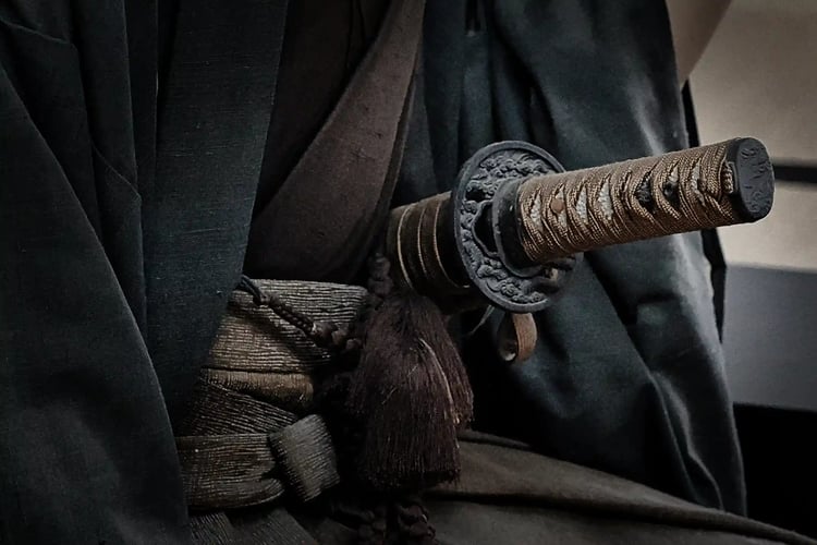 A Japanese sword concealed (or hidden) in his robes (or kimono)