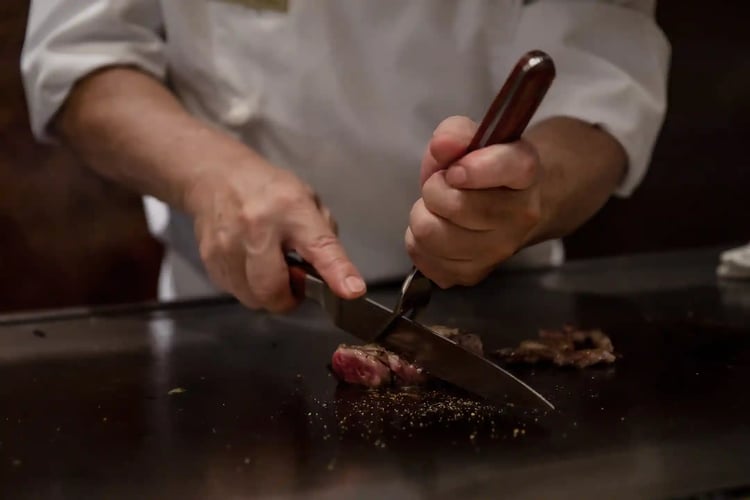 Chef cooking Kobe beef on a griddle teppan