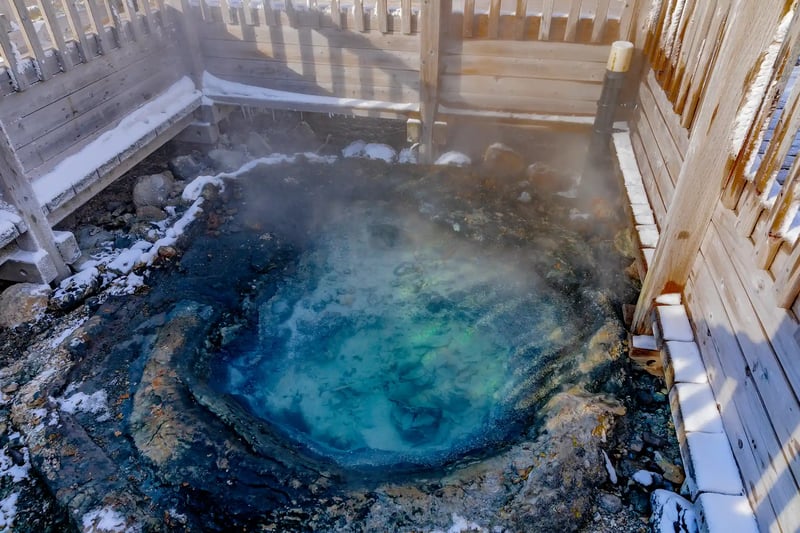 The steaming Tessen-ike geyser in the snowy landscape of Hell Valley