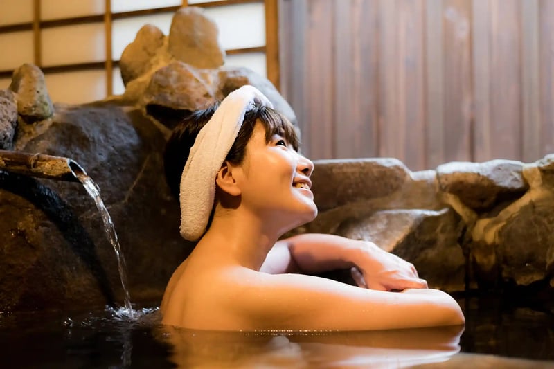 A woman unwinding in the hot spring waters of a traditional rock bath