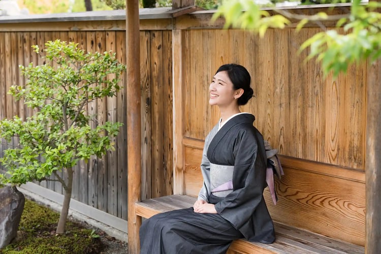 A woman in a kimono sitting gracefully in a Japanese garden