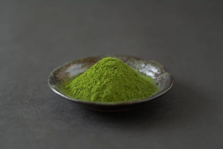 Matcha powder in a small dish on a black background