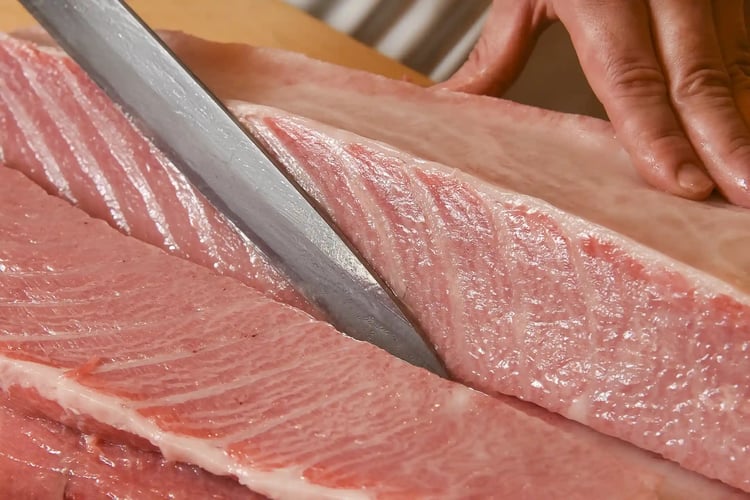 A sushi chef preparing a whole tuna