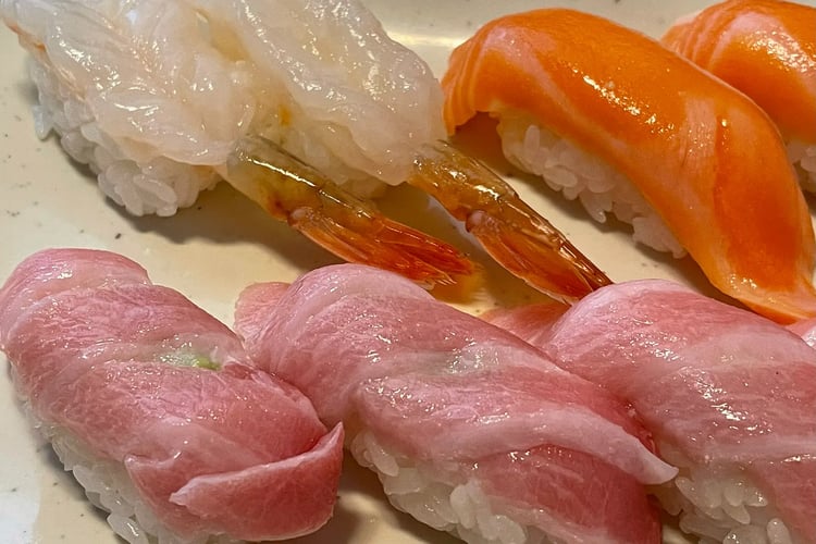 A Close-Up of a Single Piece of Nigiri Sushi Placed on a Wooden Counter