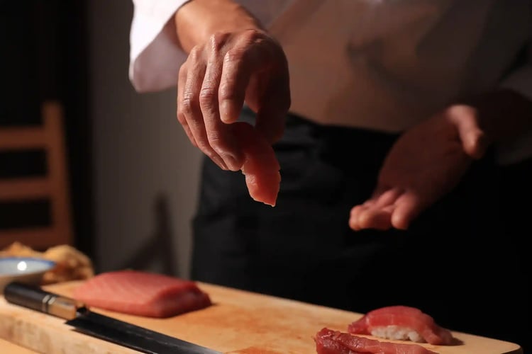 A Sushi Chef Presenting a Piece of Tuna (Maguro) Sushi