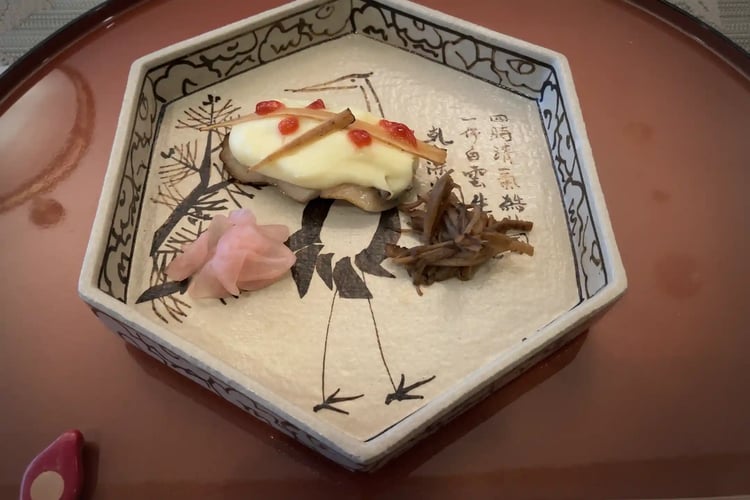 One course from a Kaiseki meal, presented in a dish adorned with a crane design