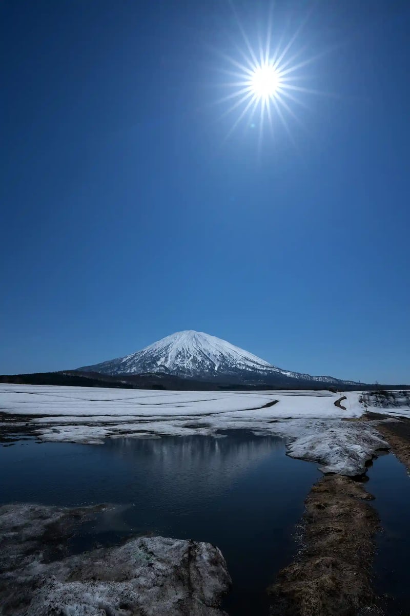 Upside-down Mt. Yotei reflected in the water with lingering snow