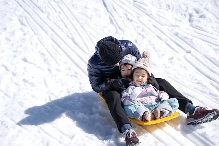 A parent and child sledding on a snowy winter slope