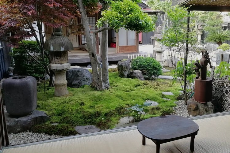 A nostalgic view from the engawa, overlooking an old water well and a chabudai table