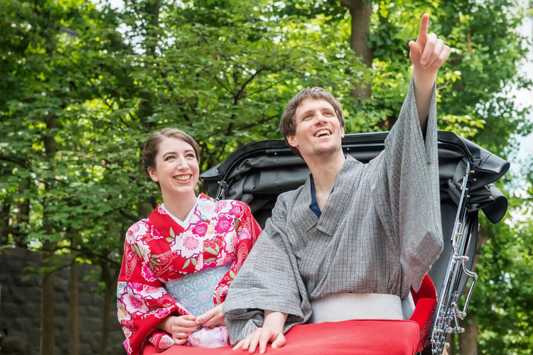 A foreign tourist couple in yukata riding a rickshaw