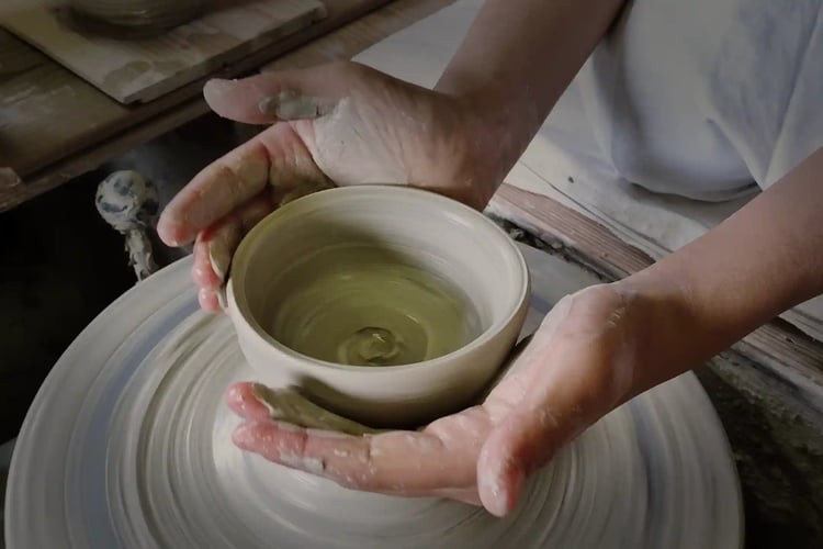 Hands shaping clay on a potter’s wheel