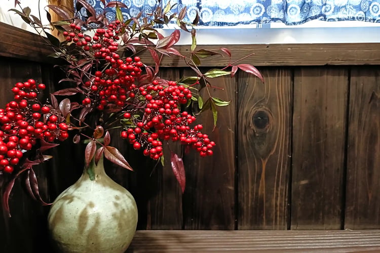 Nanten berries arranged in a vase against a wooden plank wall