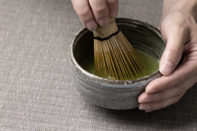 A Bowl of Matcha Green Tea and a Bamboo Whisk