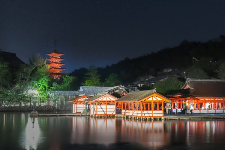 Itsukushima Shrine and the five-storey pagoda lit at night above the water