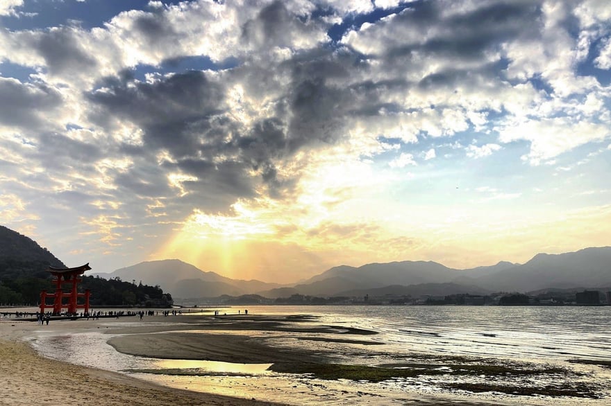 The Great Torii at low tide with the sun setting behind the mainland hills
