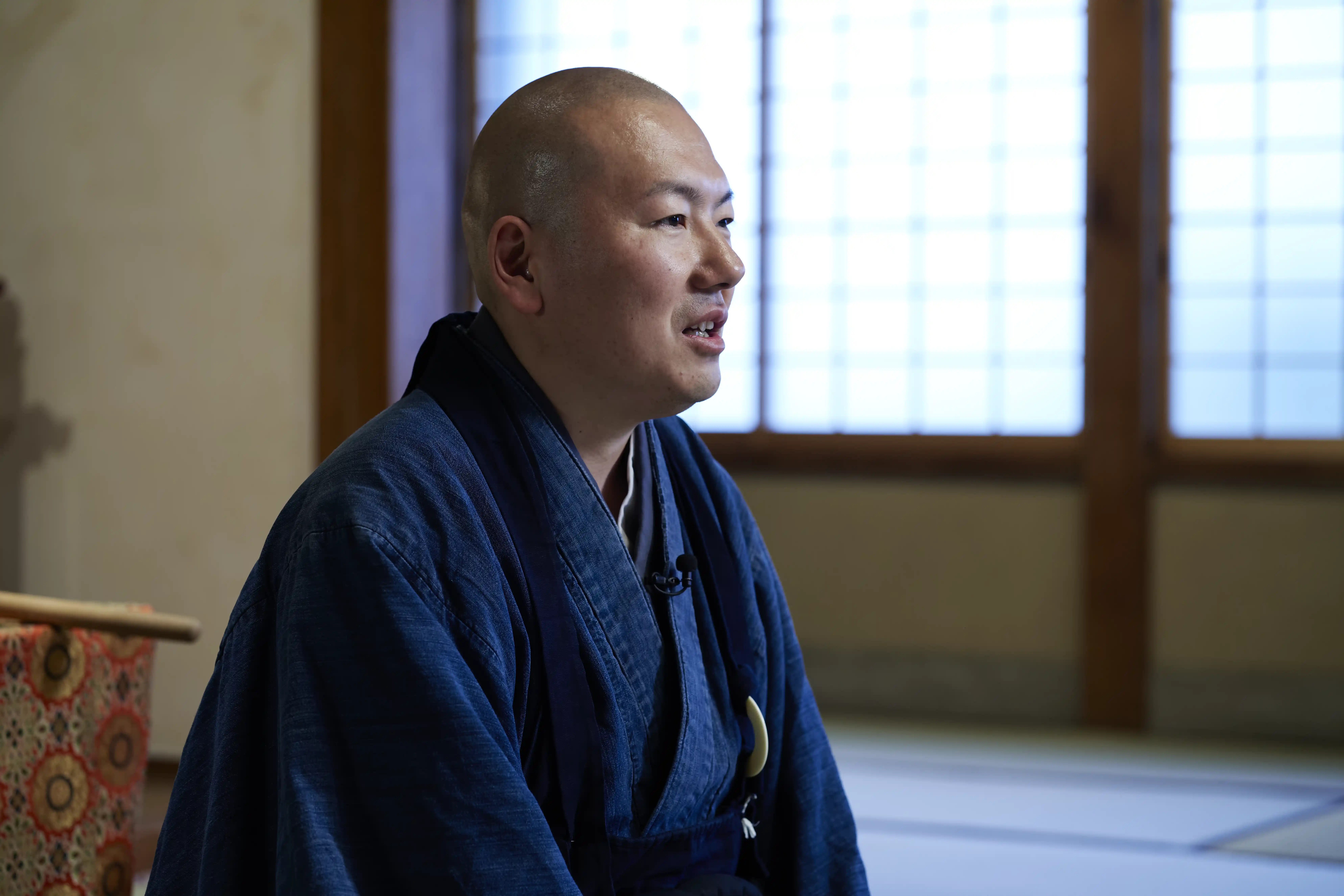 Rev. Taijun Namiki in profile, speaking in front of shoji windows at Kinryuji in Asakusa