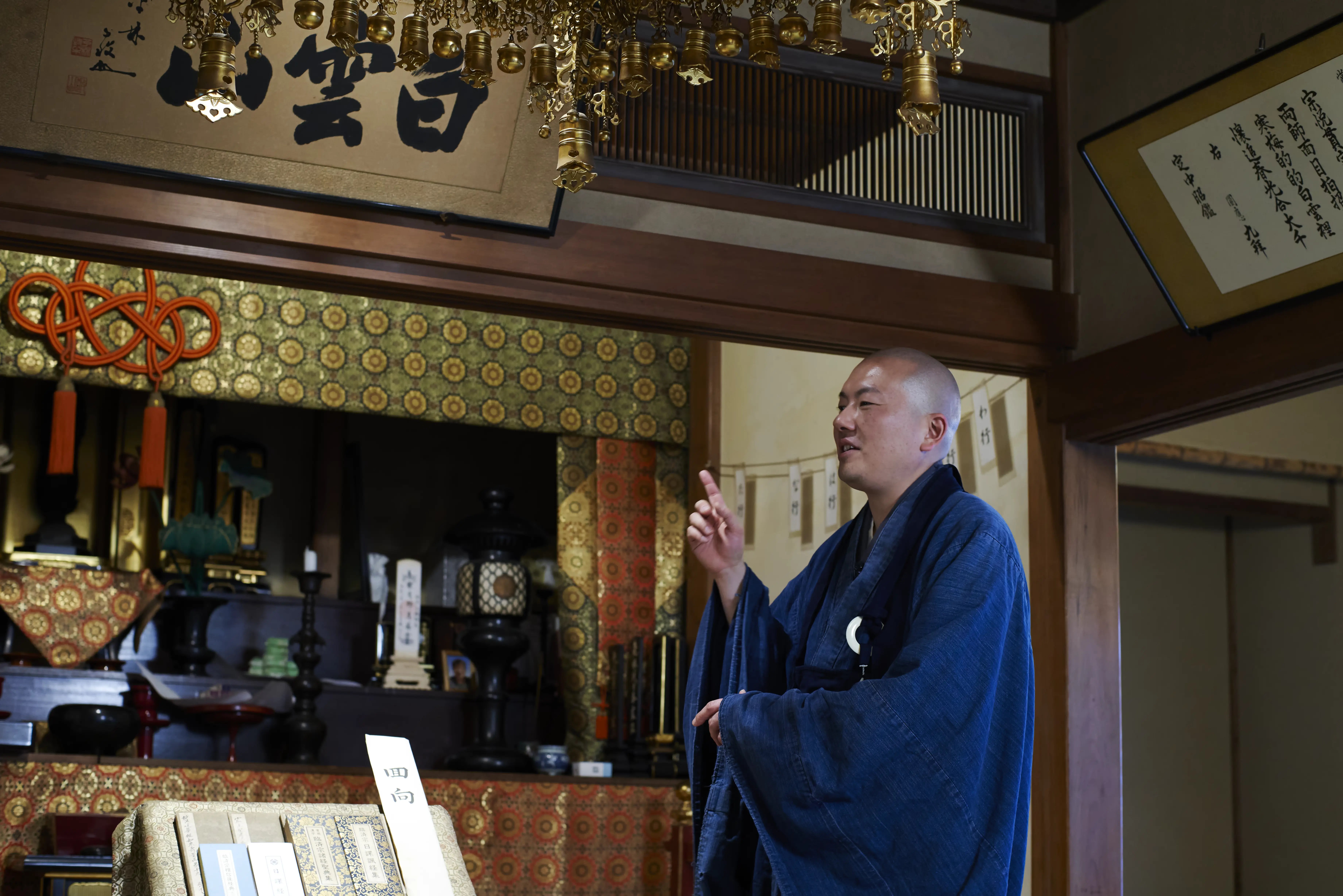 Rev. Taijun Namiki speaking in Kinryuji's main hall, beneath framed calligraphy and hanging gilt temple ornaments
