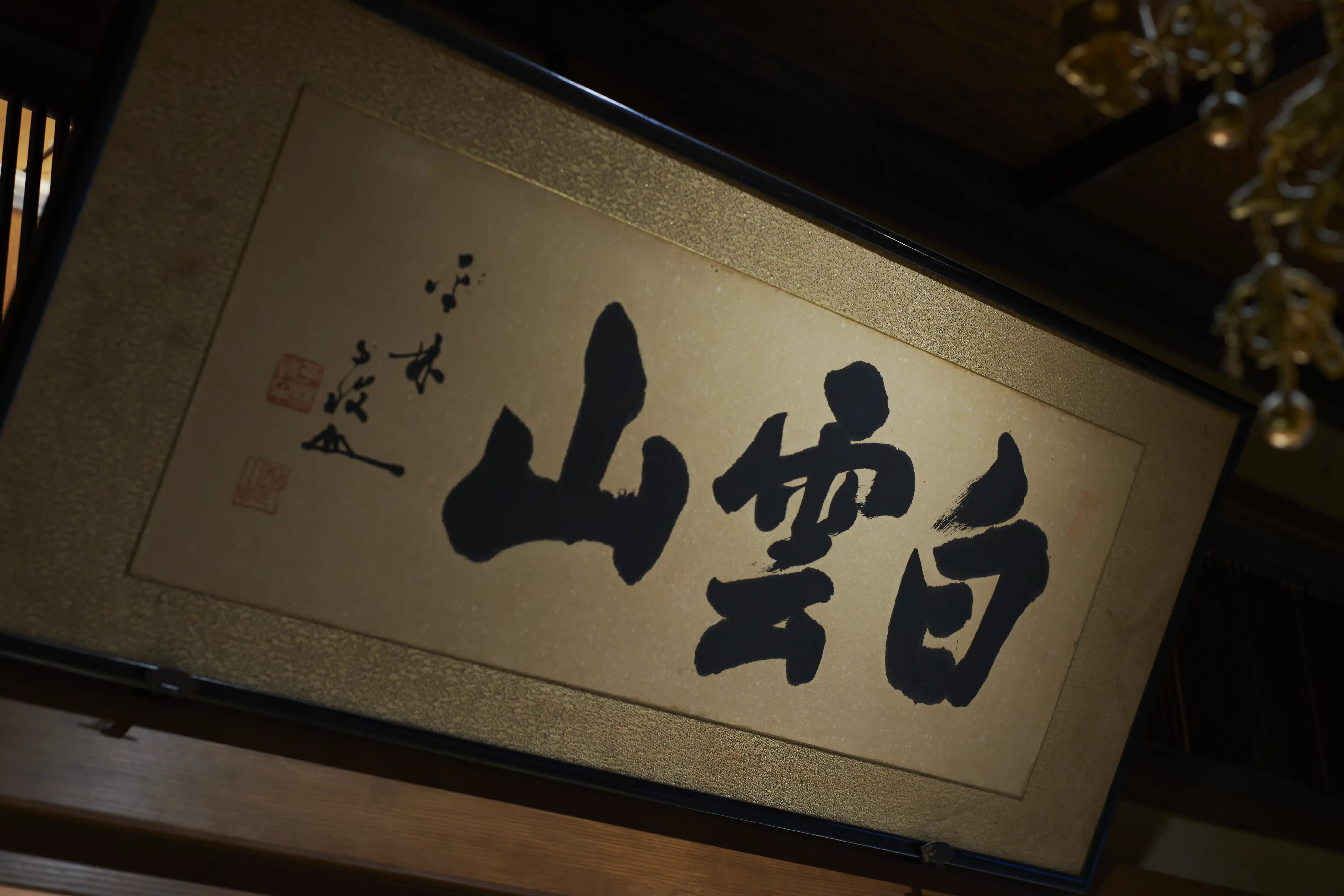 Framed brush calligraphy of three large characters hanging high in the main hall of Kinryuji, a Rinzai Zen temple in Asakusa