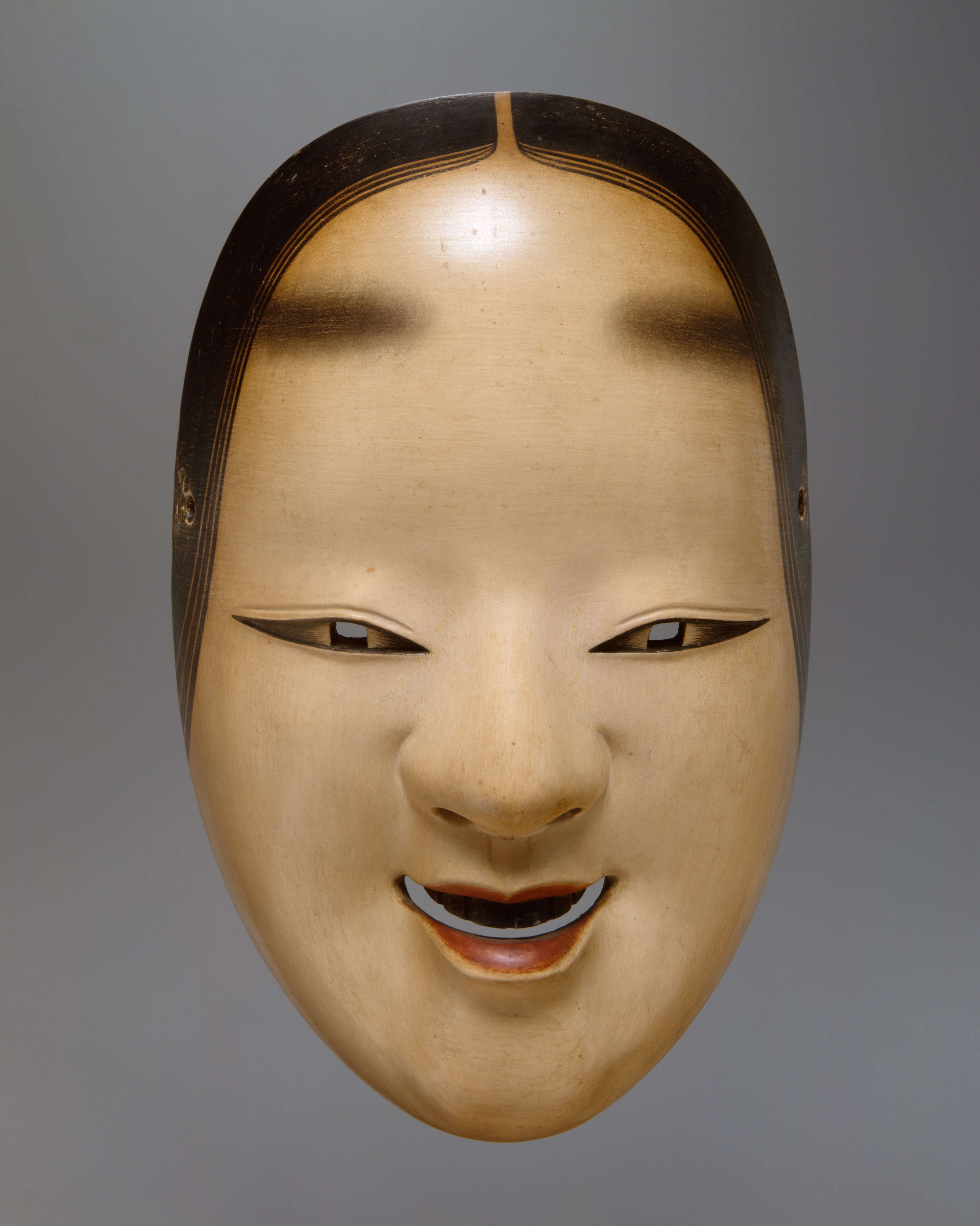 An eighteenth-century ko-omote noh mask in the Metropolitan Museum of Art, cypress wood painted white with a dark hairline and a faint parted smile