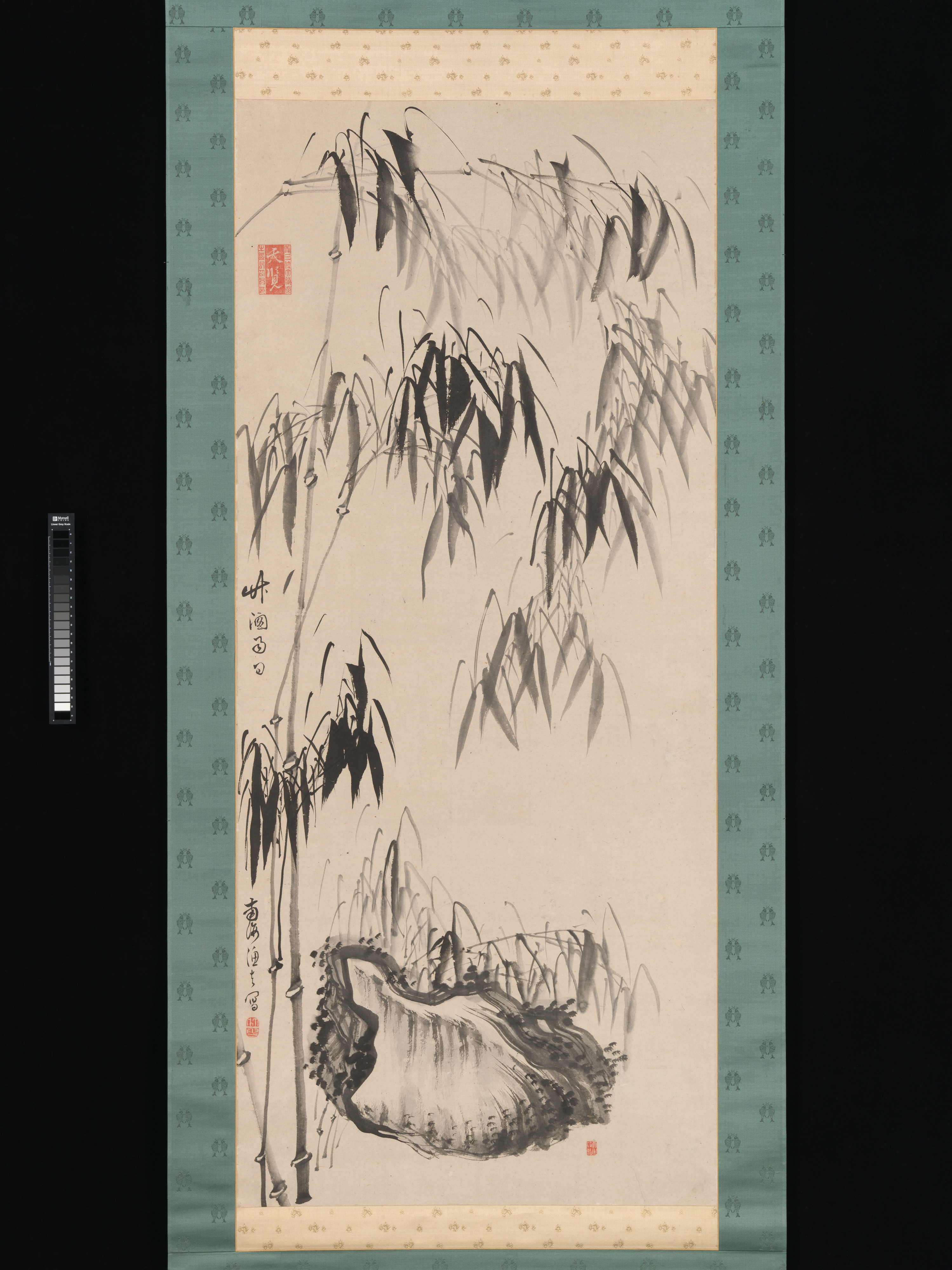 An eighteenth-century hanging scroll by Gion Nankai in the Metropolitan Museum of Art, ink on paper: bamboo leaves in dark ink above a rock in wet grey wash, with a large red seal at the upper left