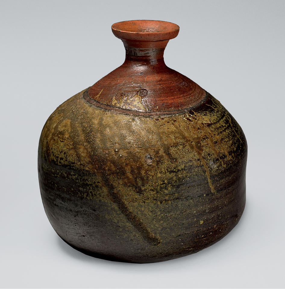 A Bizen sake bottle of about 1600 in the Metropolitan Museum of Art, its wide dark body running from olive-green ash glaze into reddish brown at the narrow neck
