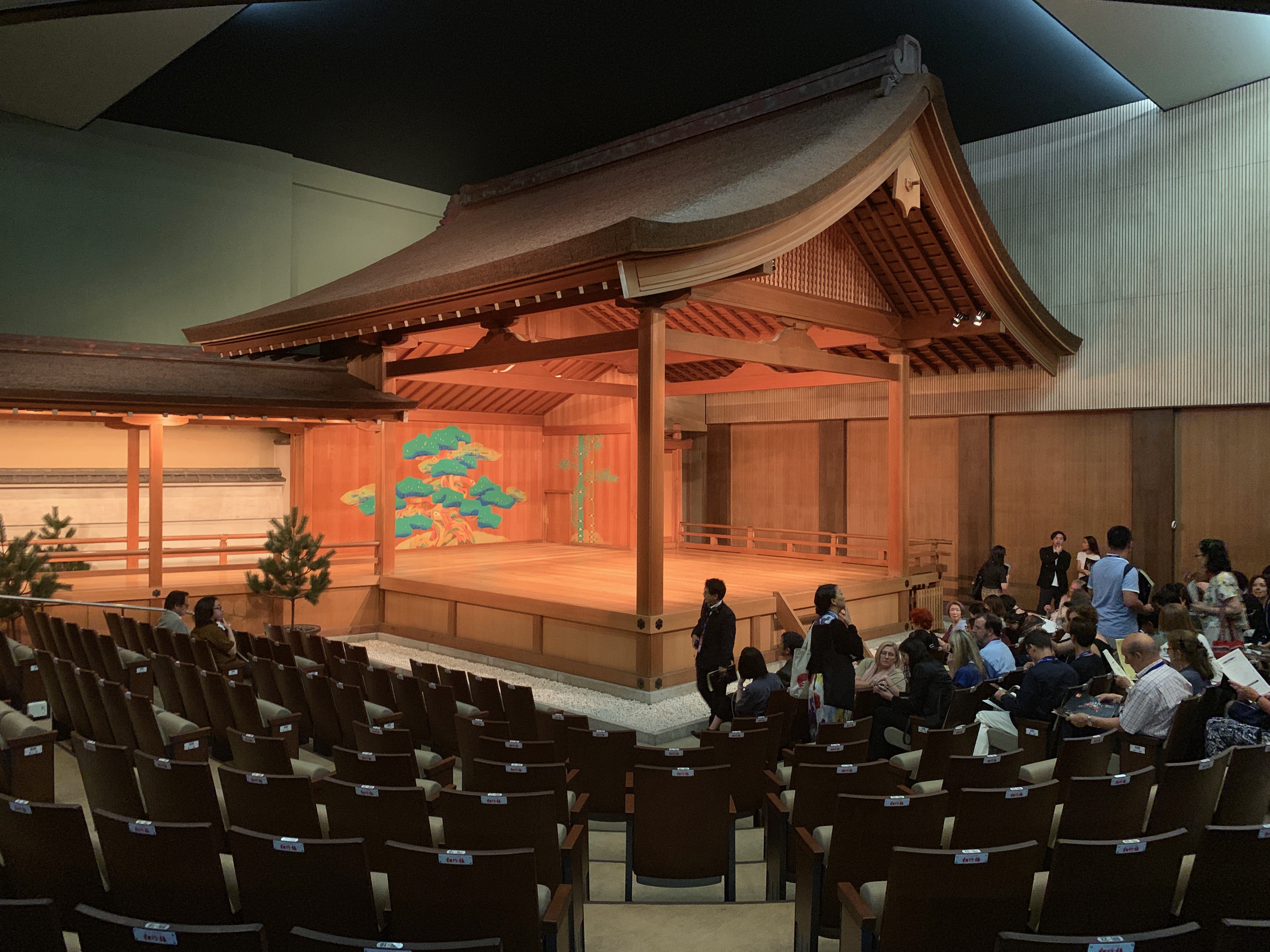 The wooden Noh stage of the Kyoto-Kanze Noh and Kyogen theatre, its painted pine backdrop lit for a performance
