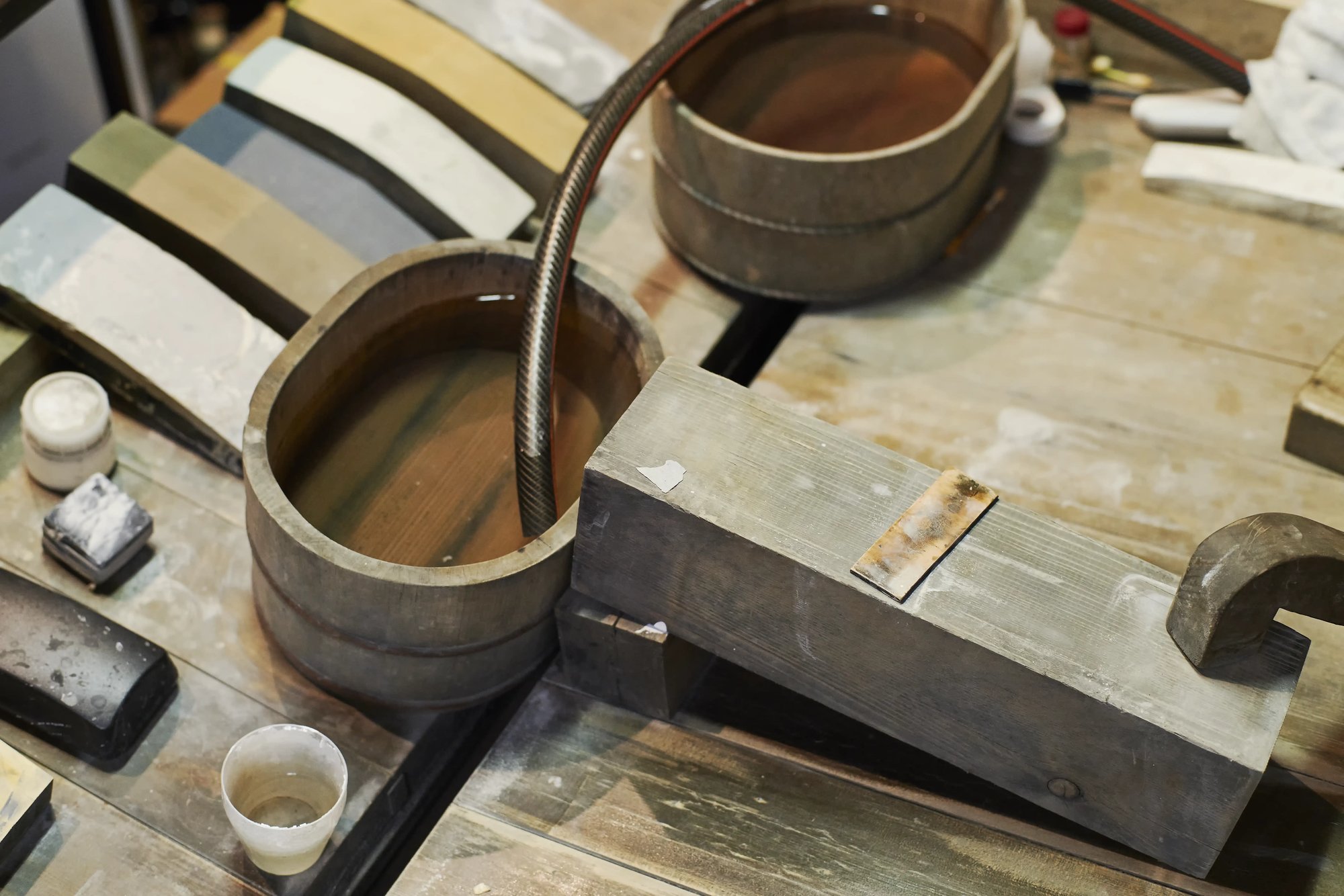 A polisher's workbench with whetstones, a water tub and a wooden blade rest