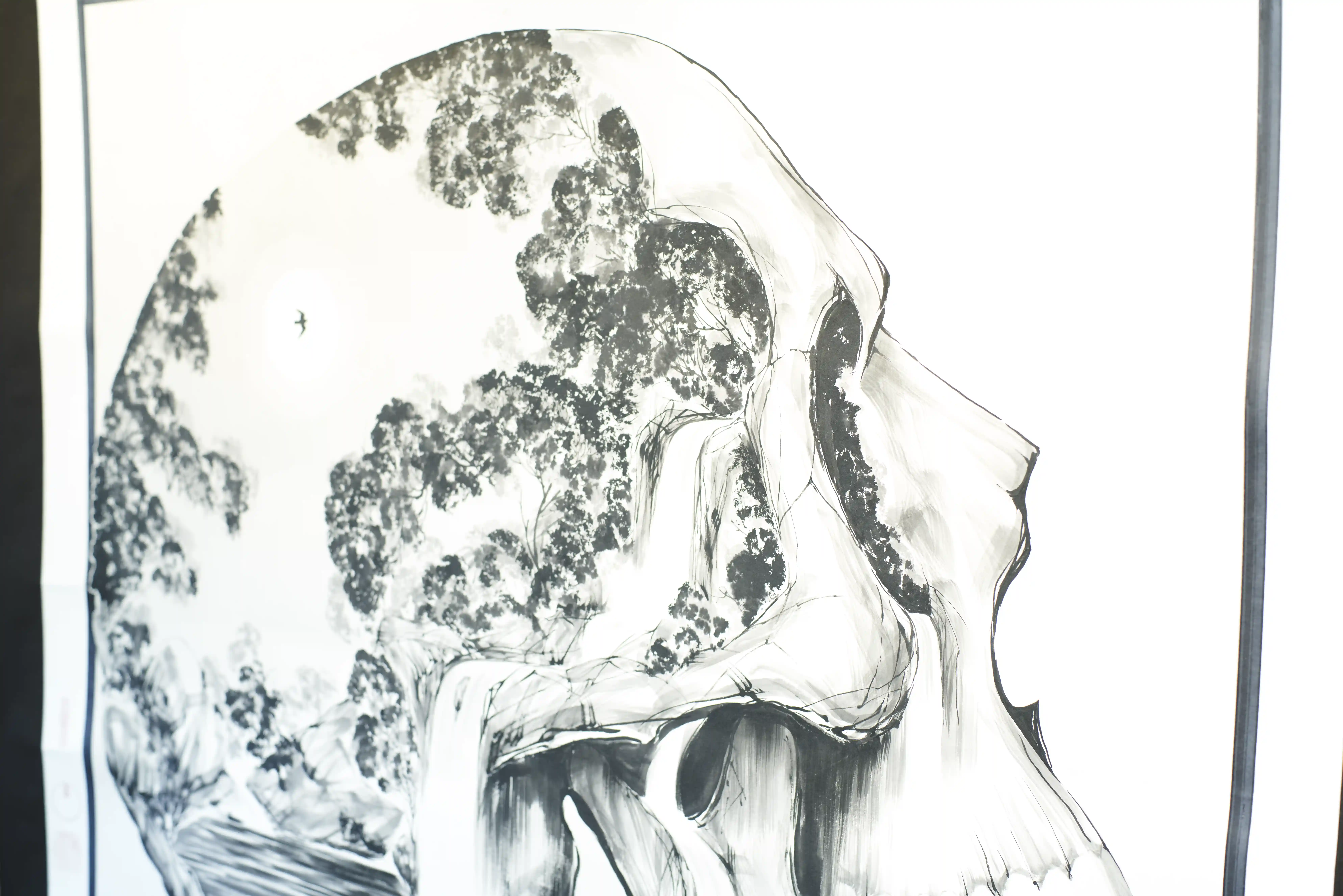 A hanging ink painting of pine and rock, the trees rendered in dense dotted strokes against large areas of untouched paper