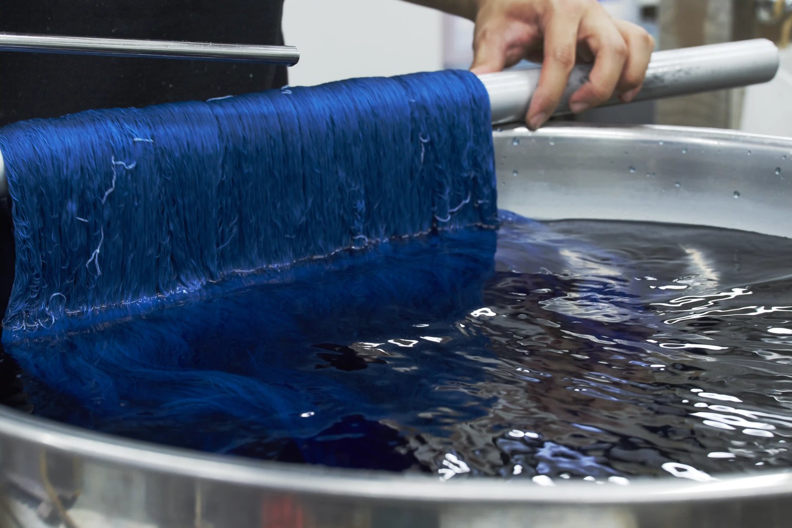 A skein of silk lifted dripping from a vat of blue dye