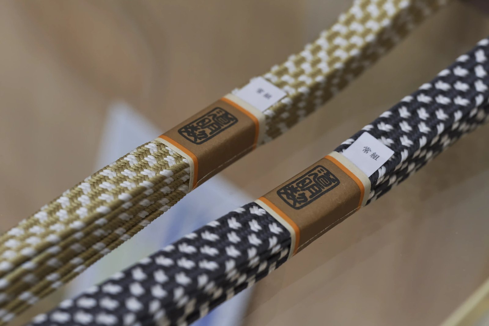 A close view of two braided silk cords, the diagonal grain of the braid visible in the pattern