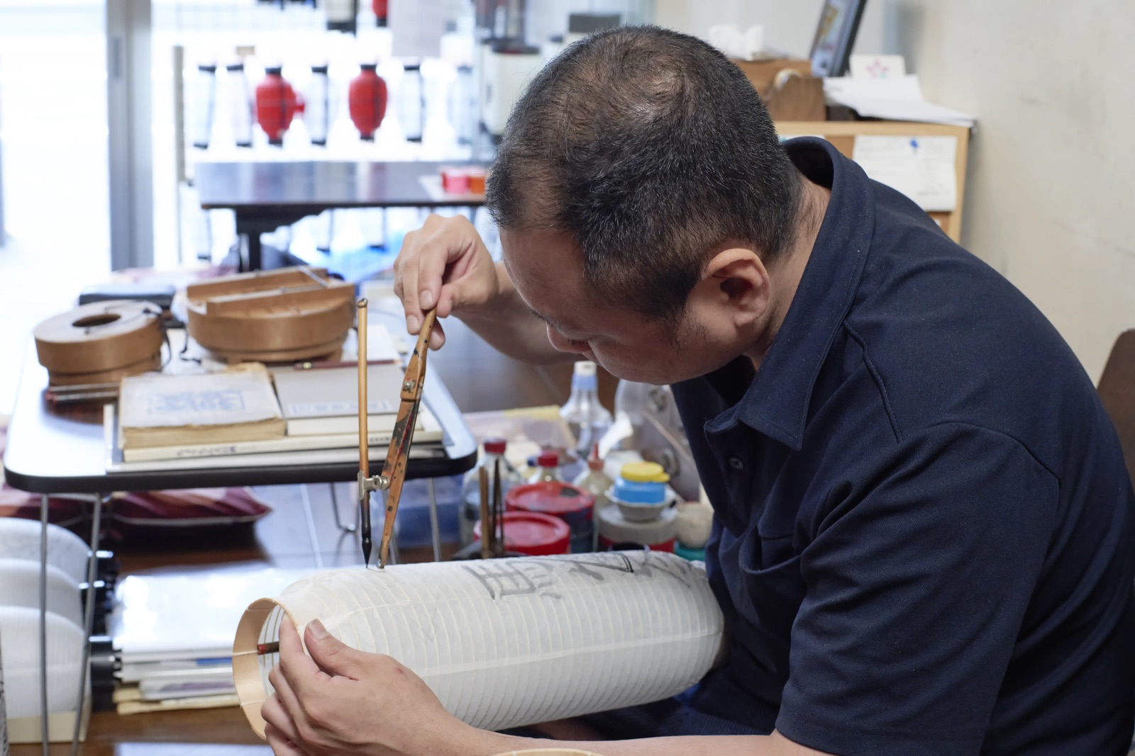 A lantern maker at his bench in the Namidabashi workshop, working on a chochin still on its forming mould