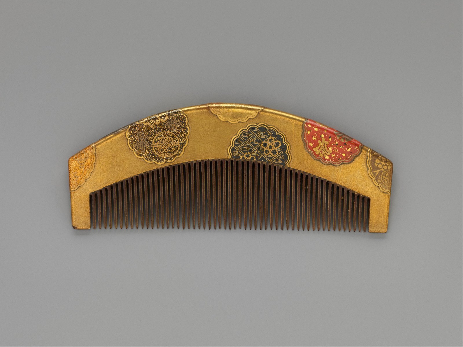 A lacquer comb decorated with flower-shaped roundels in gold, silver and red