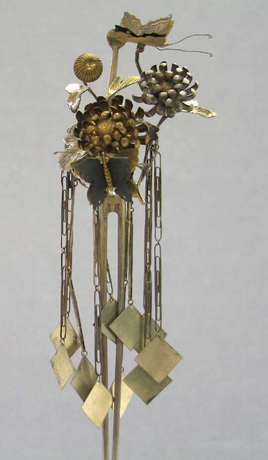 A silver-gilt hair ornament, its flowering head built up above a curtain of hanging chains