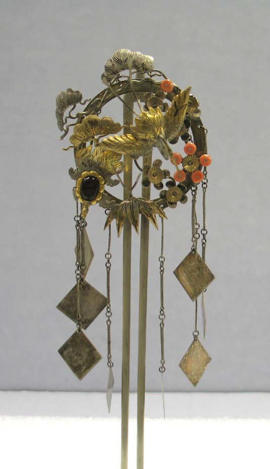 A silver and silver-gilt hair ornament, its head worked above long hanging elements