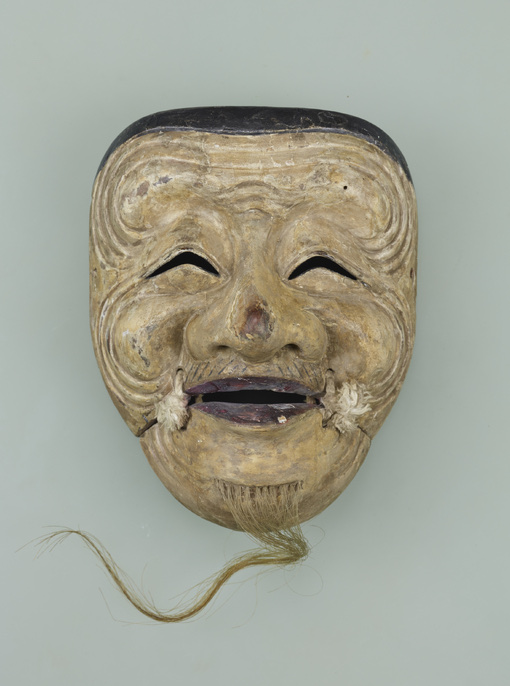 A Muromachi-period noh mask of the Okina type, photographed straight on against a plain ground