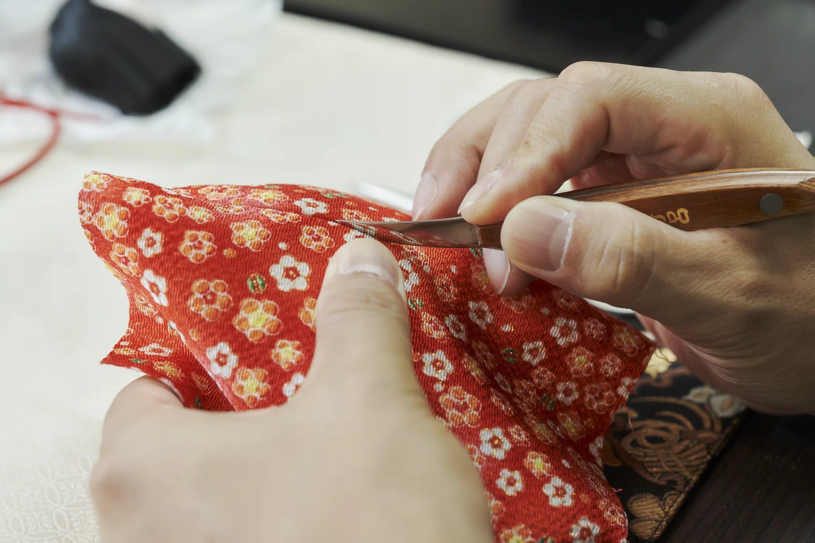 A craftsman's hands cutting a narrow groove into a moulded doll body with a small blade