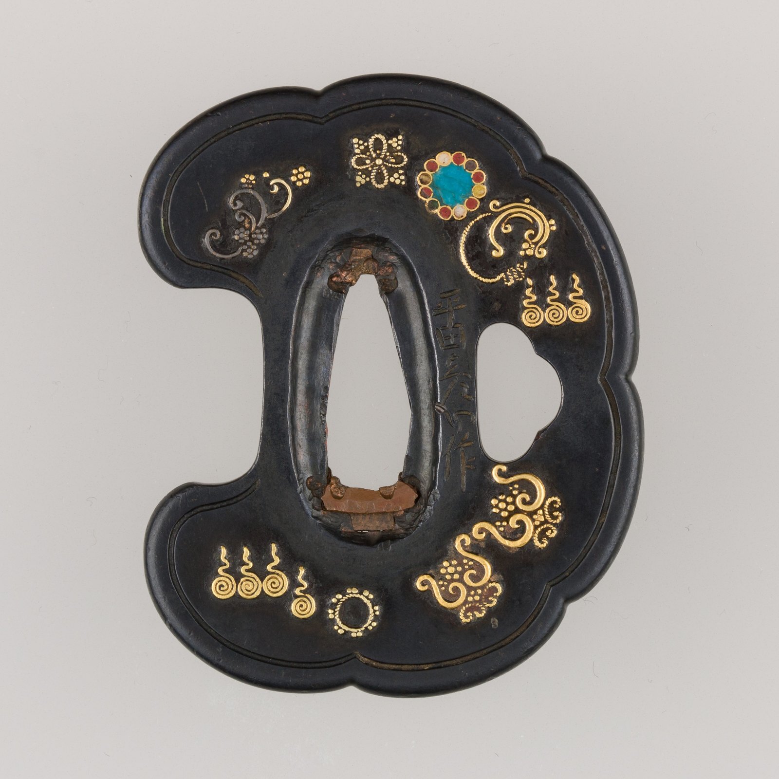 An iron sword guard inlaid with gold and enamelled cloisonne, the decoration scattered across a lobed plate