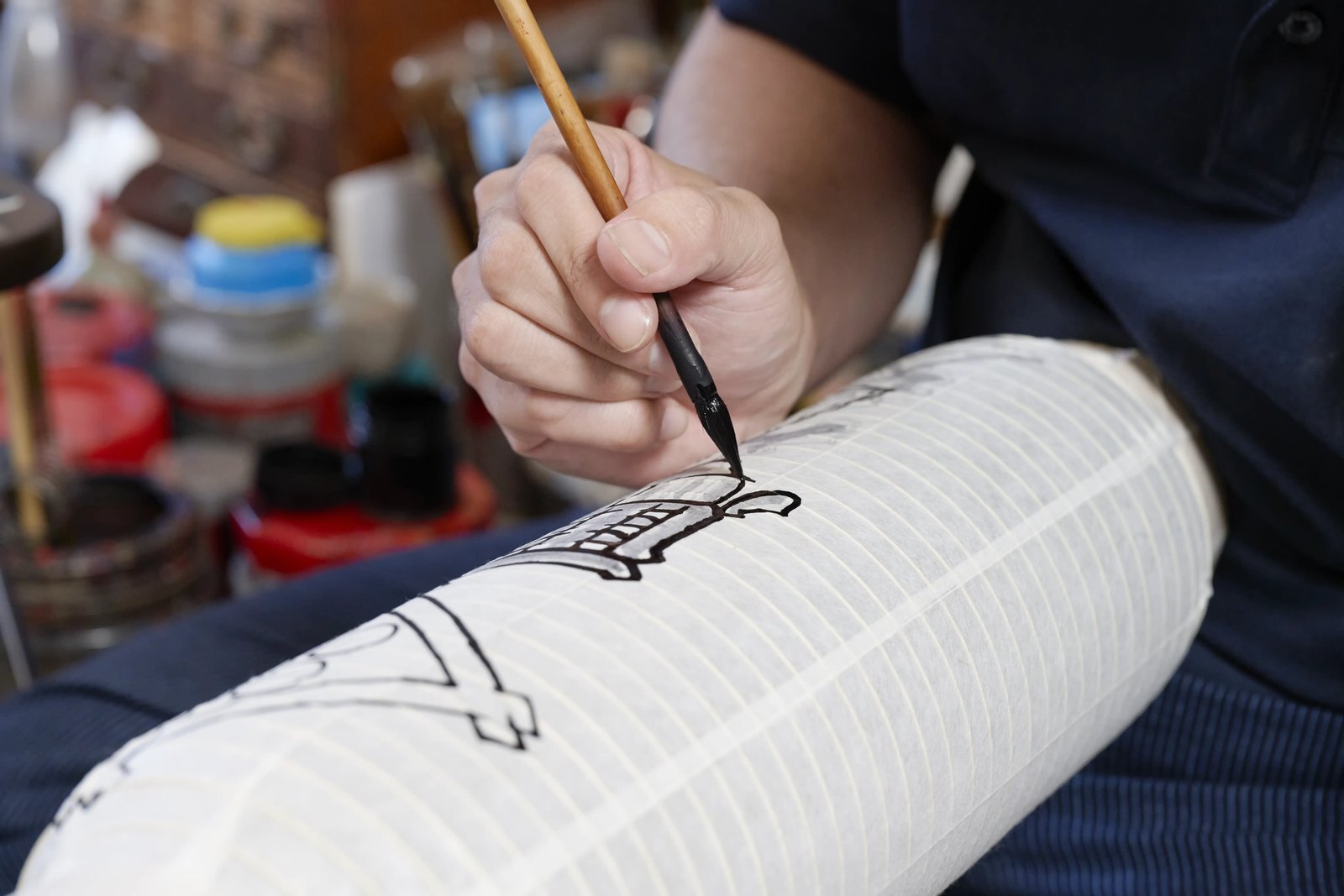 A brush laying down the first outline on a blank lantern before the characters are filled in