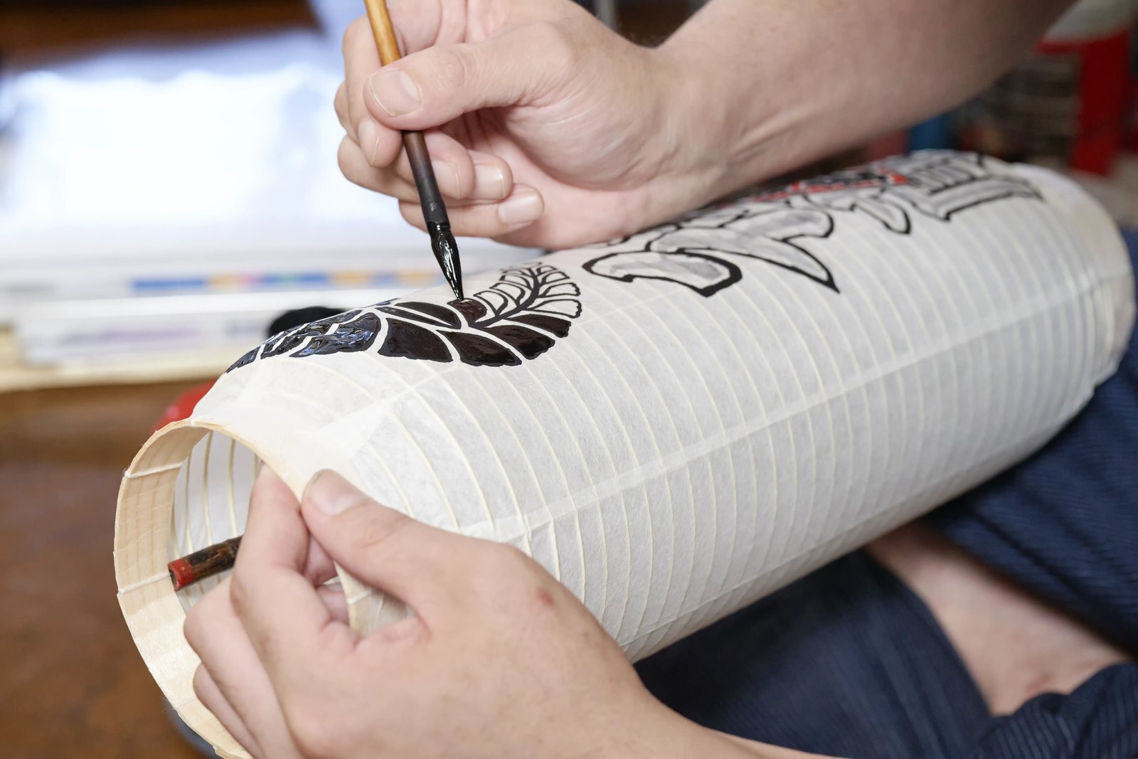 Close view of a lantern's paper surface stretched over its spiral bamboo ribs as a hand steadies it
